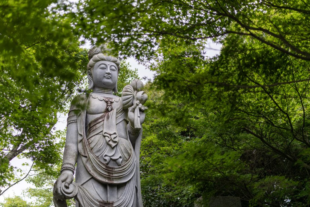 緑の木々に囲まれた如意輪寺かえる寺の観音像