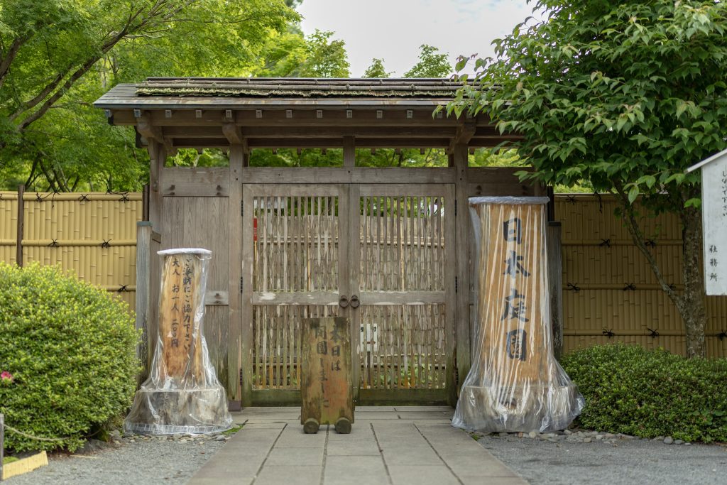 祐徳稲荷神社の日本庭園入口にある木製の門と案内板の写真