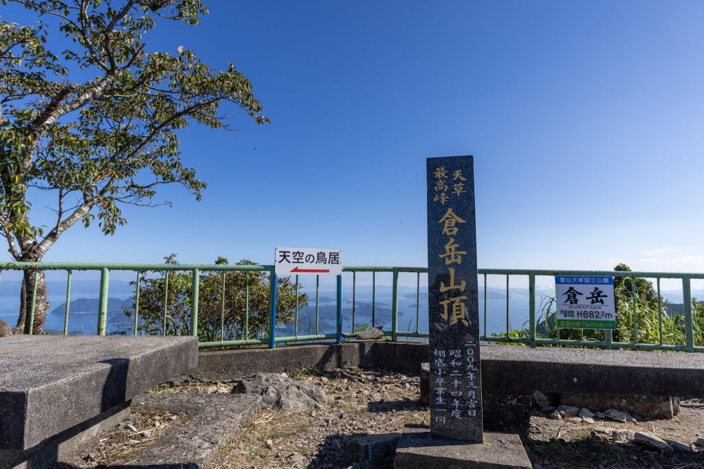 倉岳山頂に立つ標高682.2メートルの石碑と天草の景色