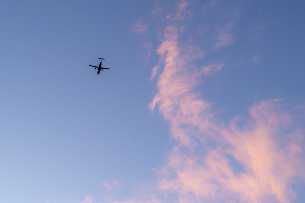 夕焼け雲が広がる青空を飛ぶ飛行機