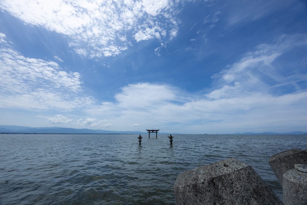海の中に立つ永尾剱神社の鳥居と石灯籠、広がる空を撮影した風景写真